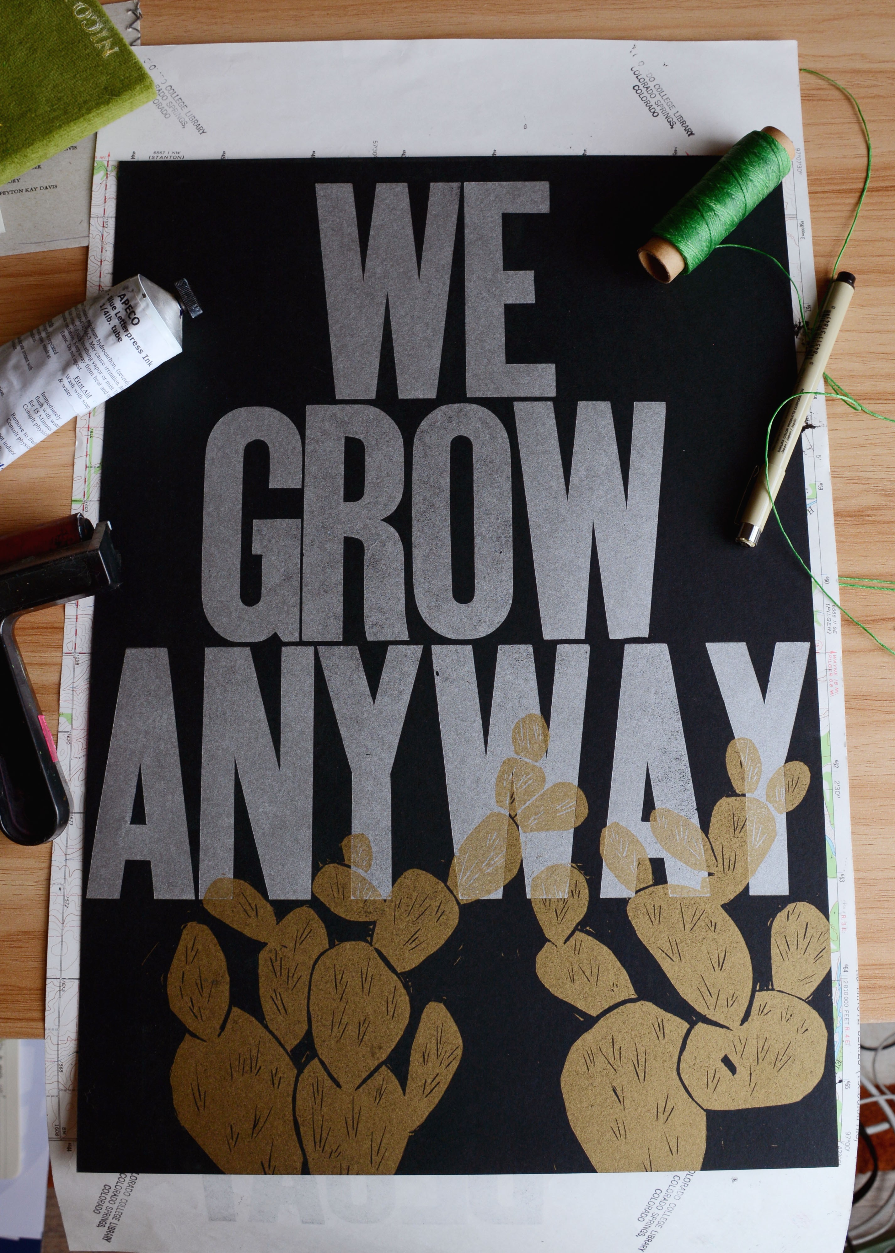 Poster with bold text reading 'WE GROW ANYWAY' and illustrations of hands holding plants.